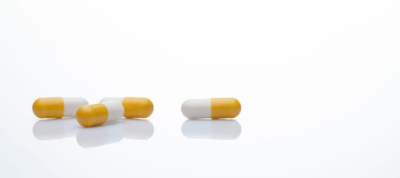 Yellow and white capsule pills on white background. Prescription drugs. Pharmaceutical industry. Health and medical care concept. Online pharmacy web banner. Pharmacology for doctors and pharmacists.
