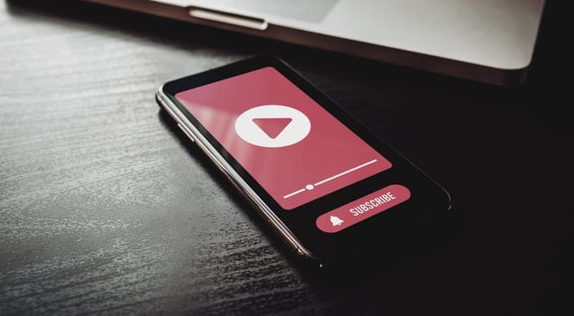 Boost video engagement with subscription reminders. Keep audience hooked with notifications and push reminders. Smartphone with subscribe bell button lying on wooden table.
