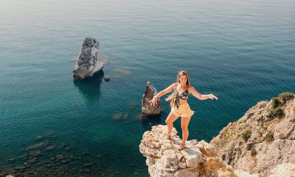 Woman travel sea. Happy tourist taking picture outdoors for memories. Woman traveler looks at the edge of the cliff on the sea bay of mountains, sharing travel adventure journey.