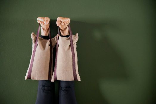 Young woman in yoga relaxing pose with legs up by a wall with heavy sand bags