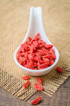 Dried Chinese wolfberries or goji berries in white spoon.