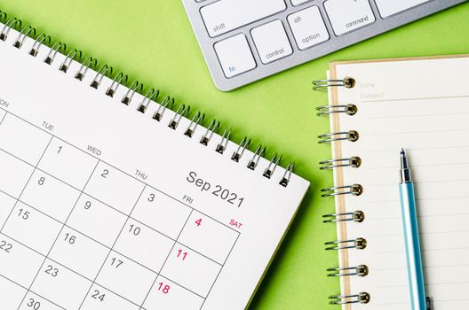 September 2021 calendar with note book on green color background.