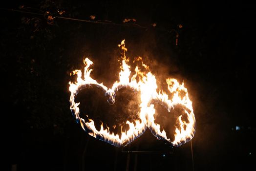 Two burning hearts at night, flame in the shape of sparkling love