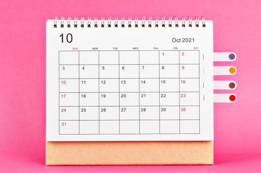 The October 2021 desk calendar on pink background.