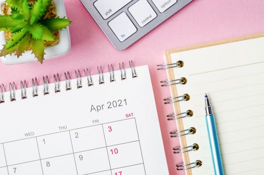 April 2021 calendar with note book on pink background.