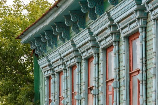 classic russian wooden house with 6 windows on it, front view poor condition on city street