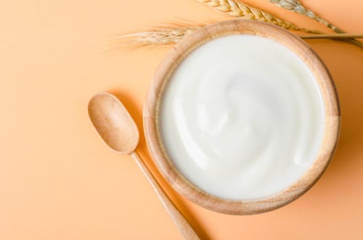 Greek yogurt in a wooden bowl and dry barley on tablecloth.