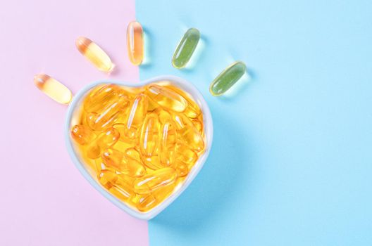 Heart-shape plate with fish oil capsules on beautiful background