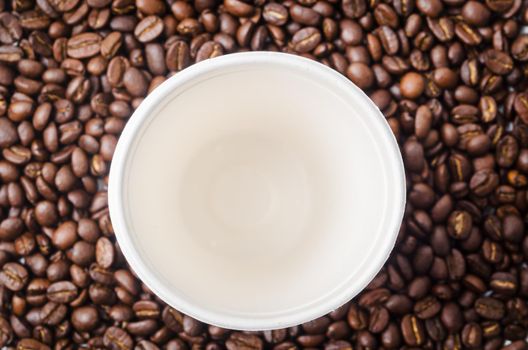 Empty paper coffee cup on coffee beans background.