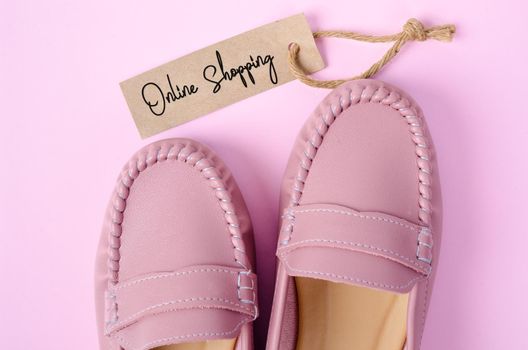 Beautiful pink women shoes with Onlin Shopping tag on pink background. Business concepts.