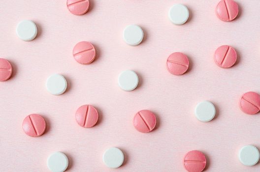 Pink and white pills macro on pink background.