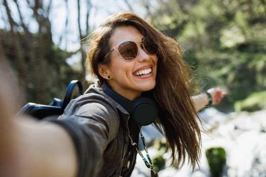 A smiling young woman making selfie while enjoying the view of nature.