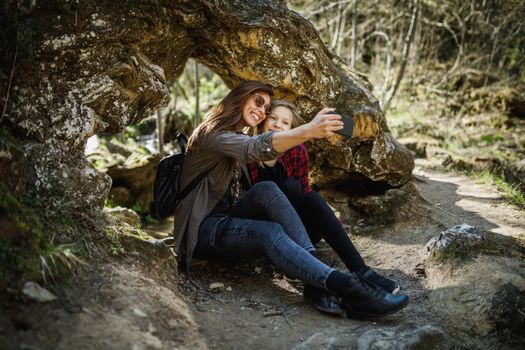 A carefree young sisters making a selfie with smartphone while enjoying in the nature.