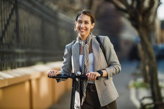 A young businesswoman with an electric push scooter going to work through the city.