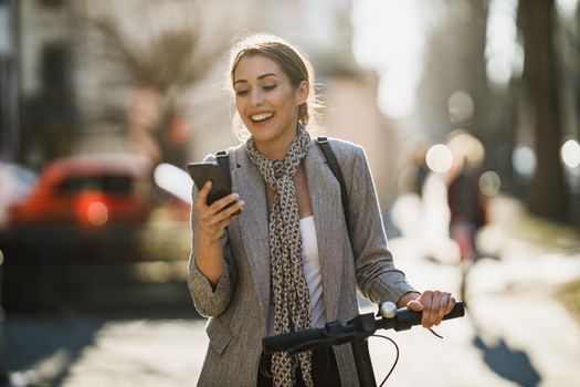 A young businesswoman with an electric push scooter going to work and using smartphone.