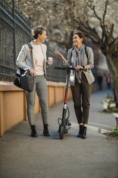 A two successful businesswomen having a quick break and chatting while walking through the city.