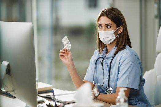 A young female nurse having video call with patient on computer in her consulting room during corona virus pandemic.