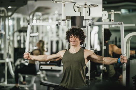 A young muscular man is doing training on machine in the gym.