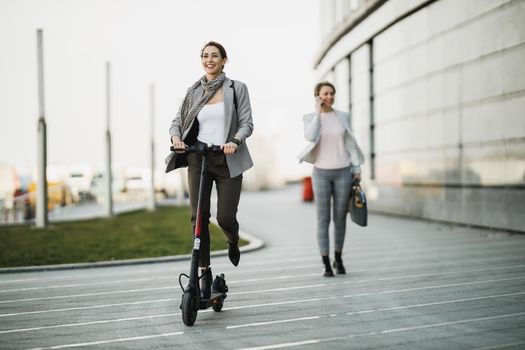 A young businesswoman riding an electric scooter on her way to work.