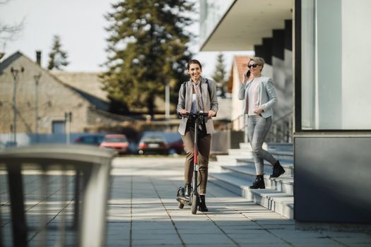 A young businesswoman riding an electric scooter on her way to work.