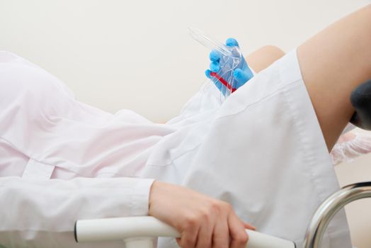 gynecologist holds a mirror for vaginal examination of the patient