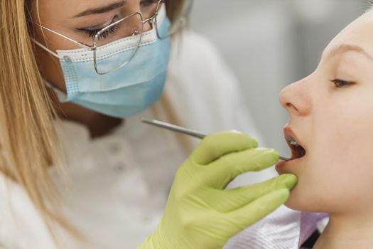 A teenager girl getting her teeth checked by dentist at dental clinic.