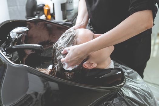 hair stylist washing woman head in hair salon
