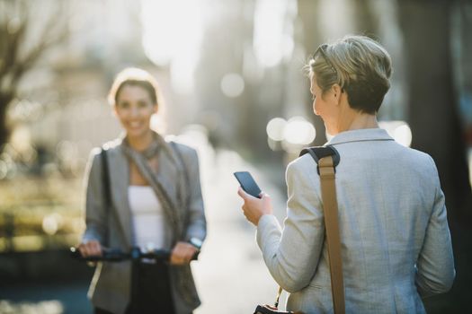 Rear view of a mature business woman surfing on a smartphone while going to work.