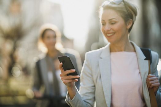 A mature business woman using a smartphone while going to work.