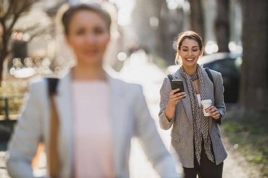 A young business woman typing on a her smart phone during quick coffe break.