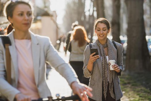 A young businesswoman using a smartphone on her way to work through the city.