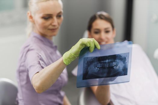 A female dentist and her young patient looking at orthopantomogram during dental appointment.