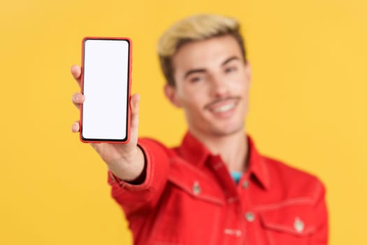 Blank screen of the mobile held by a gay man in studio with yellow background