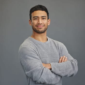 Portrait of happy man with mockup, arms crossed and ideas on studio backdrop in casual fashion. Relax, confidence and face of male on grey background with happiness, pride and smile with promo space