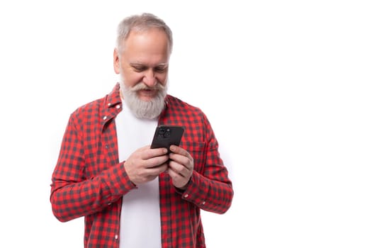 joyful successful 60 year old gray-haired pensioner man with a beard and mustache masters telephone technique.