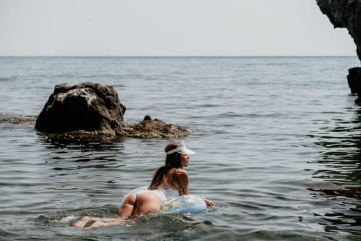 Woman summer sea. Happy woman swimming with inflatable donut on the beach in summer sunny day, surrounded by volcanic mountains. Summer vacation concept