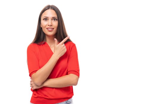 young cute caucasian brunette in a red short-sleeved shirt points with index fingers at the space for advertising.