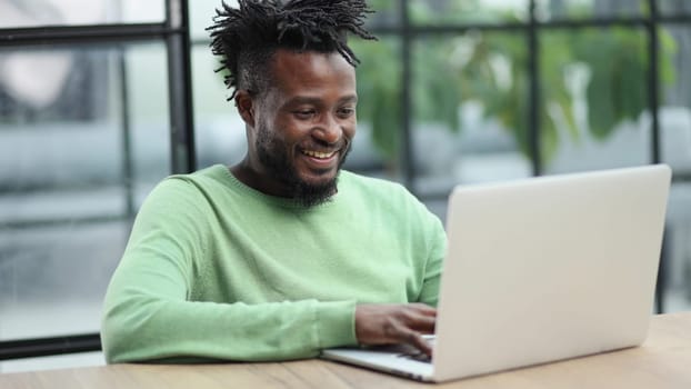 Young african american business man sitting in loft office or cafe, working on new online IT startup project, using laptop