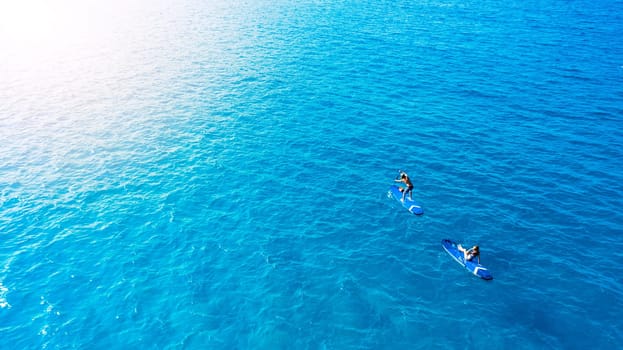 As blue as blue gets. a man and woman paddle boarding across the sea