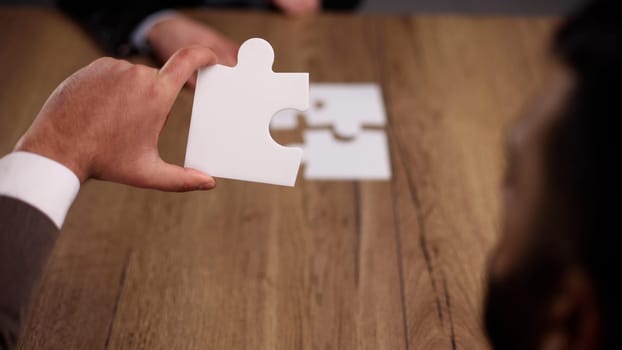 close up.business partners putting together a puzzle ,sitting at office Desk