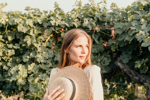 Woman at autumn winery. Portrait of happy woman holding glass of wine and enjoying in vineyard. Elegant young lady in hat toasting with wineglass smiling cheerfully enjoying her stay at vineyard