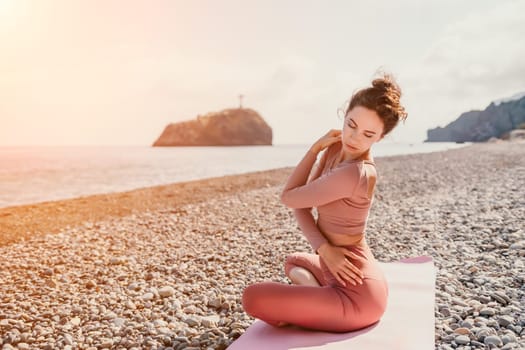 Young woman with long hair in white swimsuit and boho style braclets practicing outdoors on yoga mat by the sea on a sunset. Women's yoga fitness routine. Healthy lifestyle, harmony and meditation