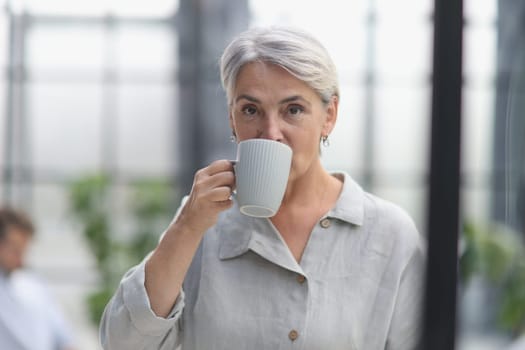 close-up mature woman holding a cup in the office.