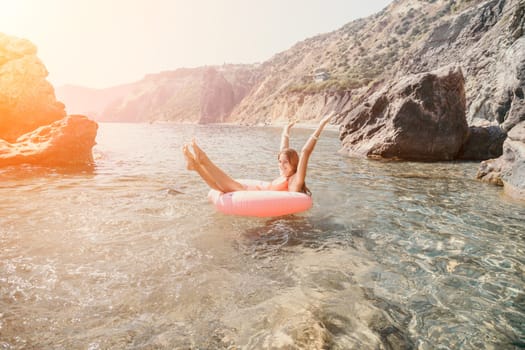 Woman summer sea. Happy woman swimming with inflatable donut on the beach in summer sunny day, surrounded by volcanic mountains. Summer vacation concept