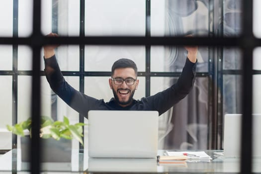 Business man sitting at his desk in the office with a laptop