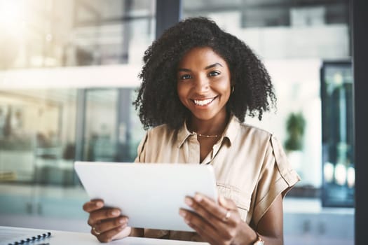 My get it done gadget. Portrait of a young businesswoman using a digital tablet at her desk in a modern office