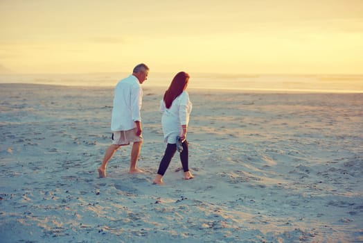 Strolls on the beach...no words needed. a mature couple going for a relaxing walk on the beach