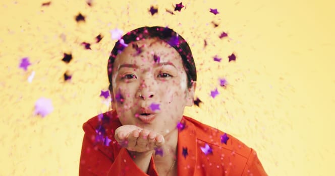 Studio, asian woman blowing confetti and celebration for birthday, anniversary or celebrating Chinese new year. Happy party, smile and model from china on yellow background to celebrate with glitter.