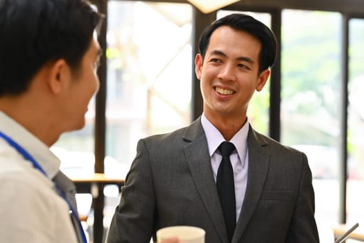 Attentive asian male manager listening to his colleague explanations during meeting.