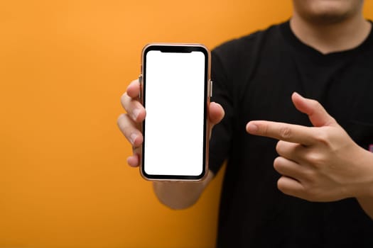 Closeup shot of hand holding smartphone over yellow background. Empty screen for your webpage or advertise text.